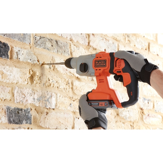 BLACKDECKER BCD900D1K cordless hammer drill in use drilling into brick wall, close-up photography.