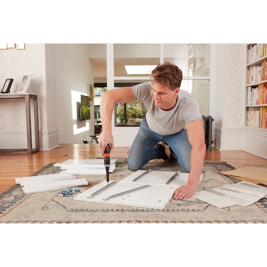 BLACKDECKER BCF601C cordless screwdriver used for assembling white furniture panels on carpeted floor.