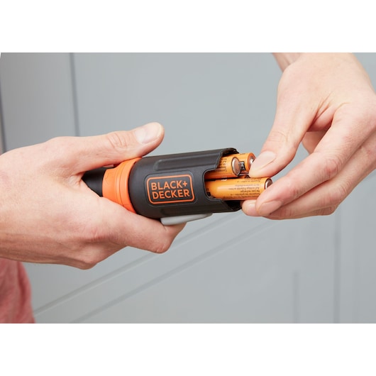 Photo of BLACK+DECKER BCF601C screwdriver with battery compartment open, showing batteries being inserted.