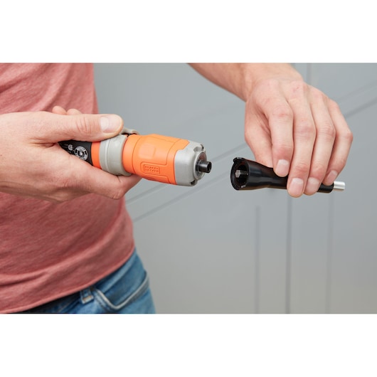 BLACK+DECKER BCF602C cordless screwdriver with orange and black body held in hands, close-up view during bit change.