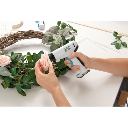 Photo of BLACKDECKER BCGL115 cordless glue gun used to attach a flower to a wreath during crafting.