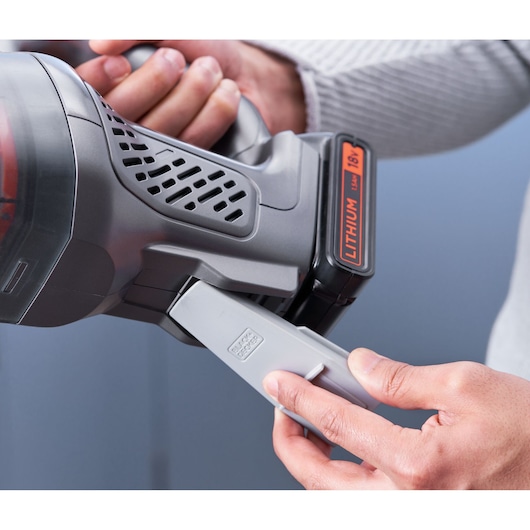 Close-up photo of BLACKDECKER BCHV001C1 handheld vacuum cleaner with hands attaching brush accessory.