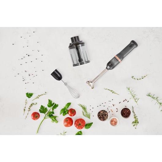 BLACK+DECKER BCKM1013KG hand blender set with whisk and chopper attachment, top view, with herbs and tomatoes.