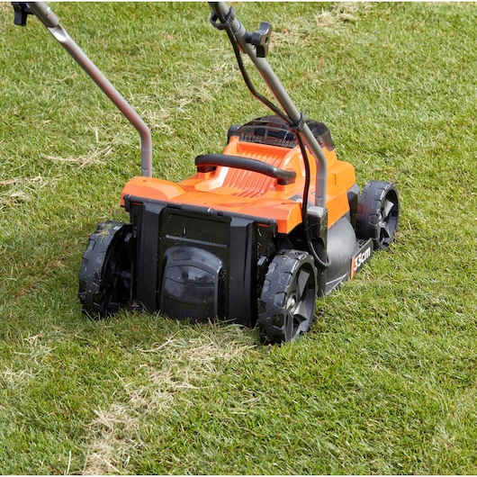 BLACKDECKER BCMW33182L2 lawn mower rear view on grass, orange and black body, 33cm cutting width.