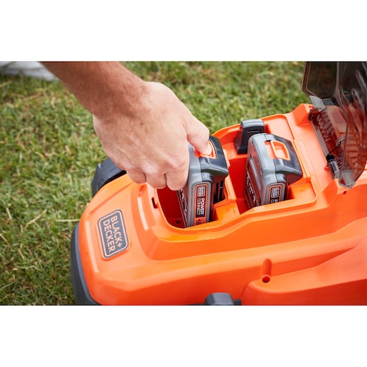 Photo of BLACK+DECKER BCMW33182L2 lawn mower battery compartment with hand inserting battery.