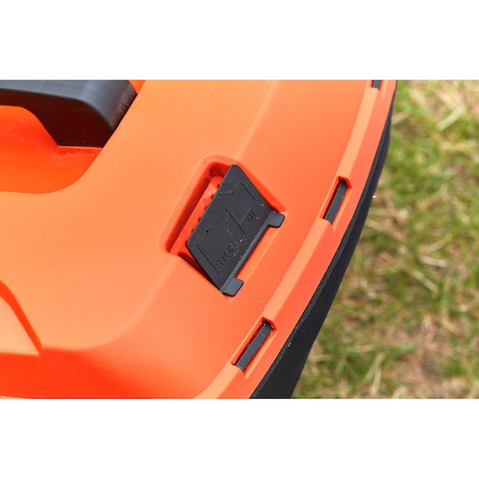 BLACKDECKER BCMW3318N lawn mower close-up showing black control switch on orange body, outdoor setting.