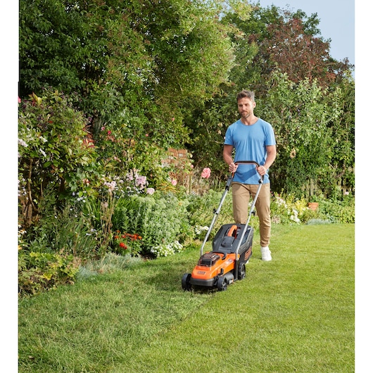 Photo of BLACKDECKER BCMW3336N lawn mower being used on grass in a garden setting.