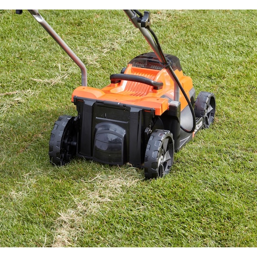 BLACKDECKER BCMW3336N lawn mower rear view on grass, orange and black body, large wheels.