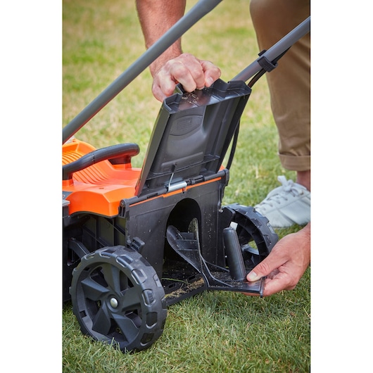BLACKDECKER BCMW3336N lawn mower with open rear chute on grass, showing maintenance access.