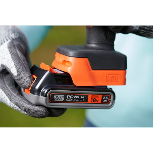 BLACKDECKER BCPP18D1 cordless tool with 18V 2.5Ah lithium battery being inserted, close-up in outdoor setting.