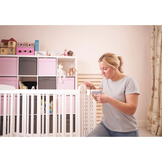 BLACKDECKER BCRTA01 baby monitor in nursery, woman holding device near crib with pink and grey storage bins.