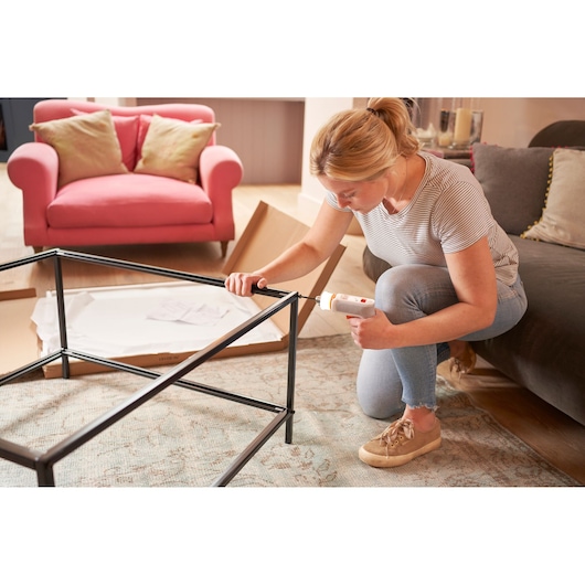 Photo of BLACKDECKER BCRTA01 cordless screwdriver used to assemble a metal table frame in a living room.