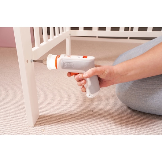 Photo of BLACKDECKER BCRTA01 cordless screwdriver in use assembling white furniture on beige carpet.