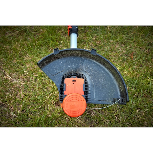 BLACKDECKER BCSTA536B grass trimmer head with black debris guard and orange spool, photographed on grass.
