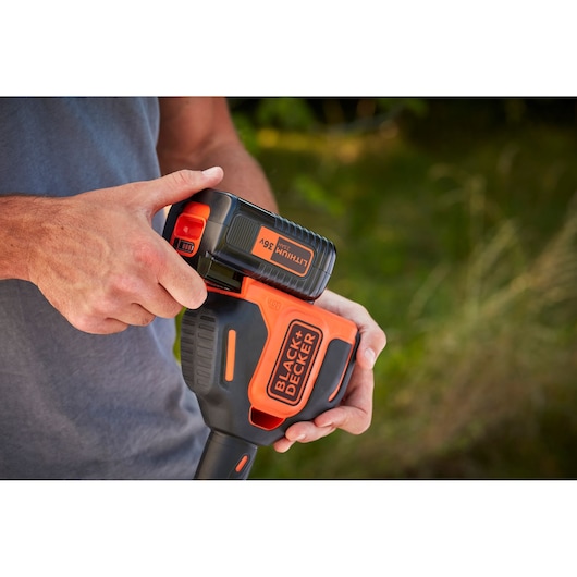 Photo of BLACK+DECKER 36V lithium battery being inserted into BCSTA536B garden tool, close-up.