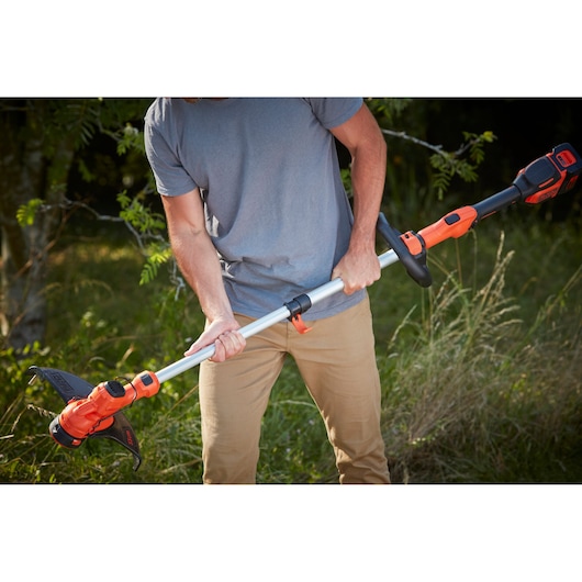 Photo of BLACK+DECKER BCSTA536B cordless grass trimmer in use outdoors, showing orange and black design.