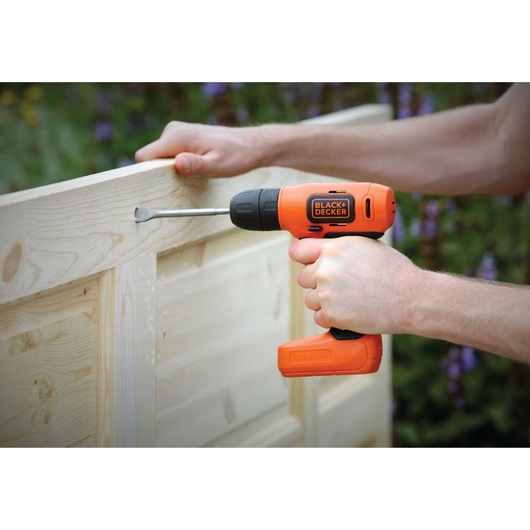 BLACKDECKER BDCD8 cordless drill in use on wooden panel outdoors.