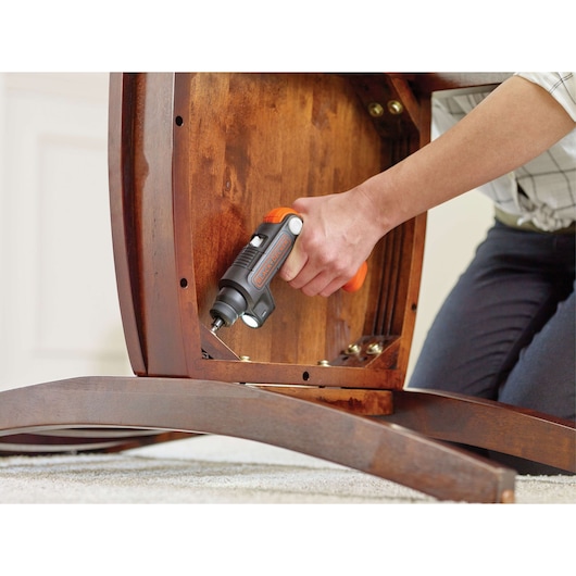 BLACK+DECKER BDCSFL20C cordless screwdriver with orange accents used to assemble wooden furniture indoors.