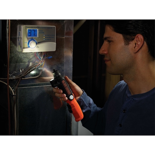 Photo of BLACK+DECKER BDCSFL20C cordless screwdriver with LED light used near an electronic control panel.