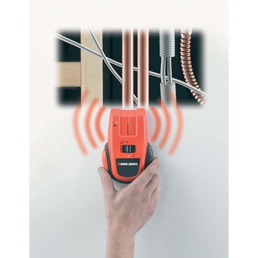 BLACK+DECKER BDS300 stud and pipe finder held on wall, showing detection signals and pipes behind surface.