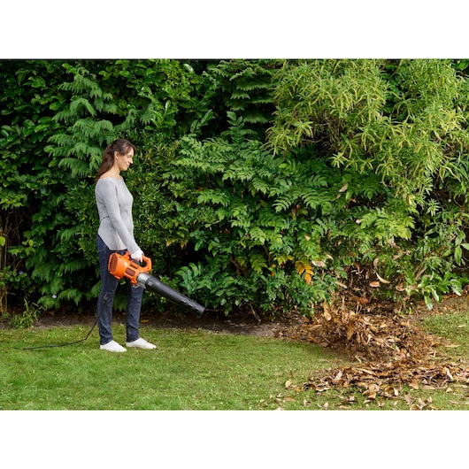 BLACKDECKER BEBL185 corded leaf blower used outdoors to clear leaves on grass.