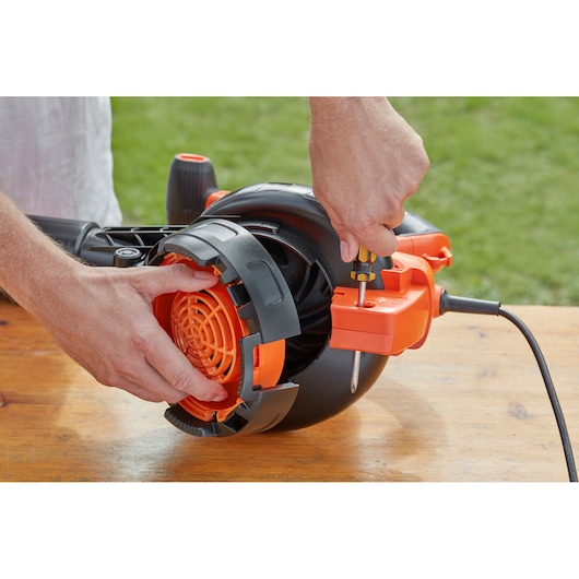 Photo of BLACK+DECKER BEBLV300 leaf blower being assembled with a screwdriver on a wooden table.