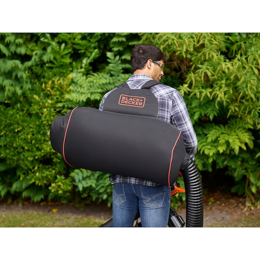 Photo of BLACK+DECKER BEBLV301 leaf blower with large black collection bag, worn on back outdoors.