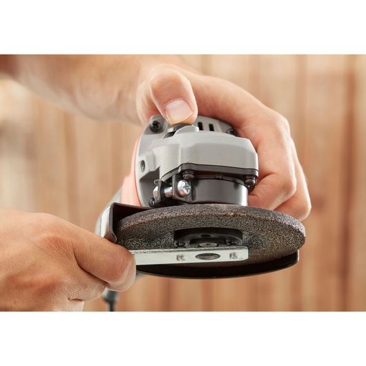Close-up of BLACKDECKER BEG010A5 angle grinder with grinding wheel, hand adjusting the tool, photography.