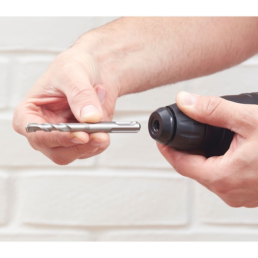 Close-up of hands inserting a drill bit into BLACKDECKER BEHS01 rotary hammer.