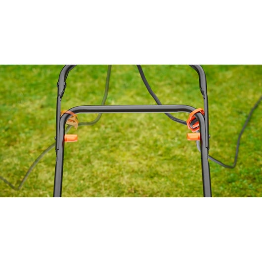 BLACKDECKER BEMW471ES lawn mower handle with orange cable clips, close-up view outdoors.