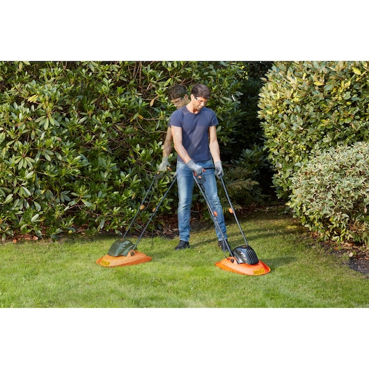 BLACKDECKER BEMWH551 lawn mowers on grass, man standing behind both, garden setting.