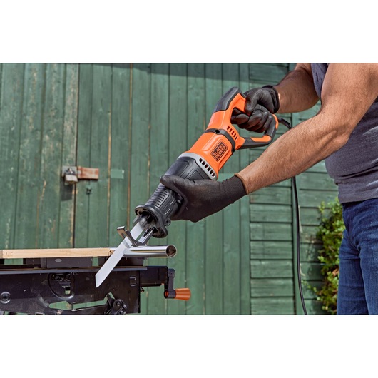 BLACK+DECKER BES301 reciprocating saw in use cutting metal pipe outdoors, close-up view.