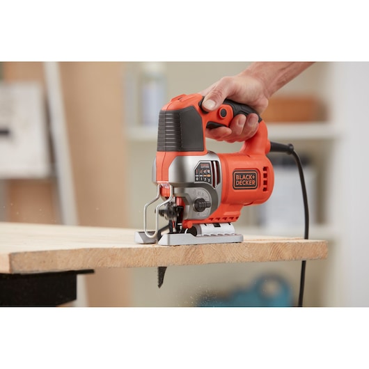 BLACKDECKER BES601 jigsaw in use cutting wood, close-up of tool held by hand.