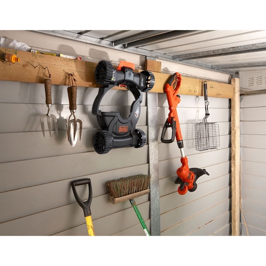 Photo of BLACKDECKER BESTA530CM lawn mower and trimmer hung on shed wall with garden tools.