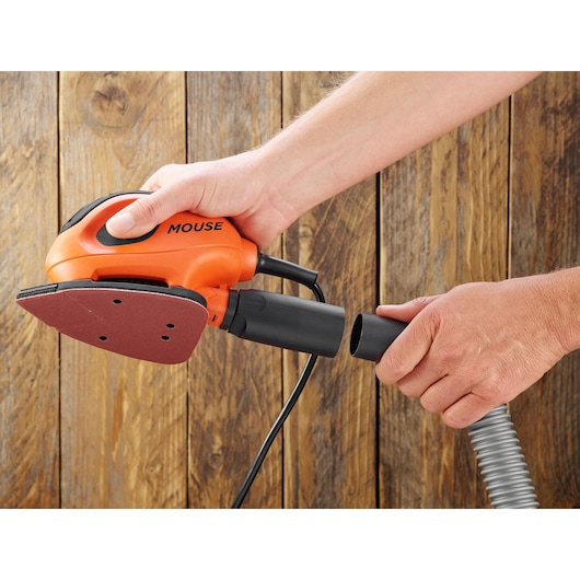 BLACKDECKER BEW230K orange mouse sander, cable and hose being connected, close-up on wood background.
