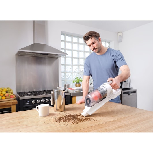 BLACKDECKER BHFEA515J cordless vacuum cleaning coffee grounds on kitchen table.