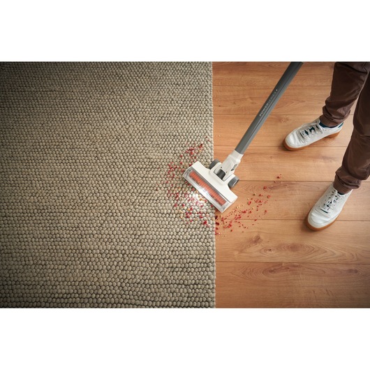 BLACKDECKER BHFEA515J cordless vacuum cleaning debris from carpet and wooden floor, top view.