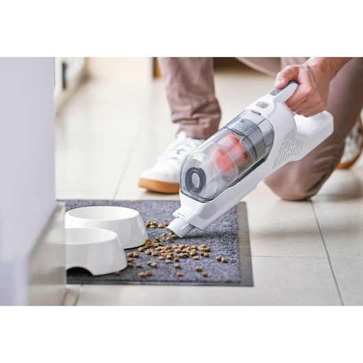 BLACKDECKER BHFEA515J handheld vacuum cleaning pet food near white bowls on a mat