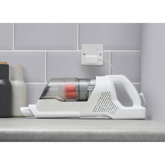 BLACKDECKER BHFEA515J handheld vacuum cleaner side view on a kitchen counter, charging with wall plug.