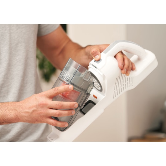 Photo of BLACKDECKER BHFEA515J vacuum cleaner with hand removing clear dust container indoors.