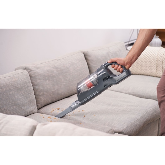 BLACKDECKER BHFEA520J handheld vacuum cleaner cleaning crumbs from a light gray sofa.