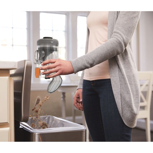 BLACKDECKER BHFEV182B vacuum cleaner bin being emptied into a trash can in a kitchen.