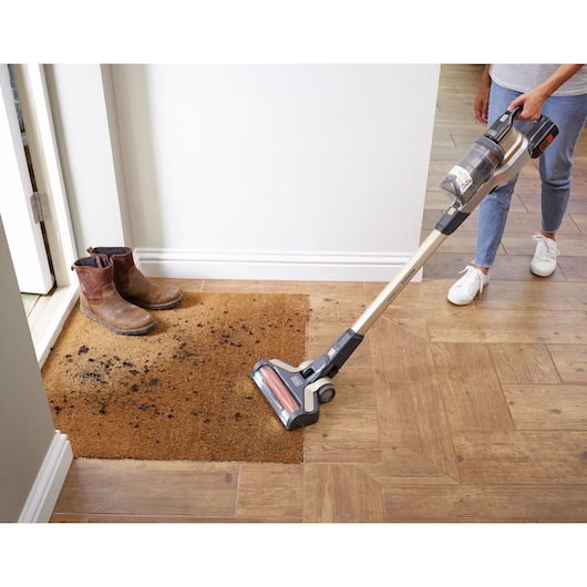 BLACKDECKER BHFEV36B2D cordless stick vacuum cleaning a dirty doormat, floor view, product in use.