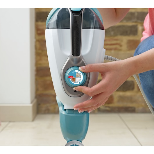 BLACKDECKER BHSM166DSM steam mop close-up with hand adjusting blue and white control dial indoors.