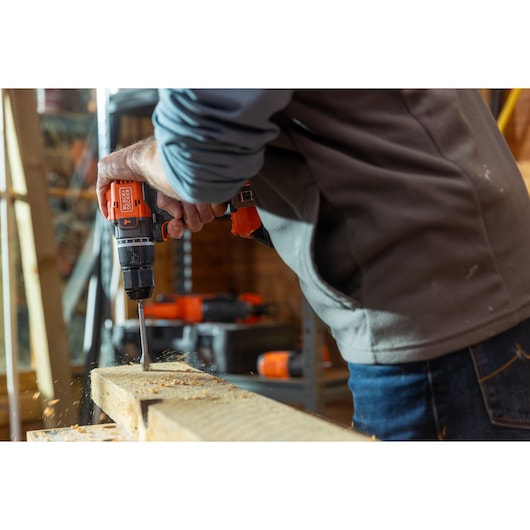 Photo of BLACK+DECKER BLD783N cordless drill in use, drilling into wood, person wearing gray jacket.