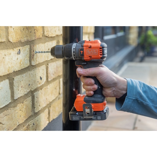 BLACKDECKER BLD783N cordless drill used to drill into a brick wall, close-up view.