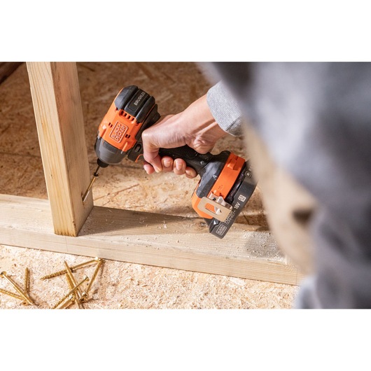 BLACKDECKER BLIM78N cordless drill in use on wooden frame, user holding tool, scattered screws visible.