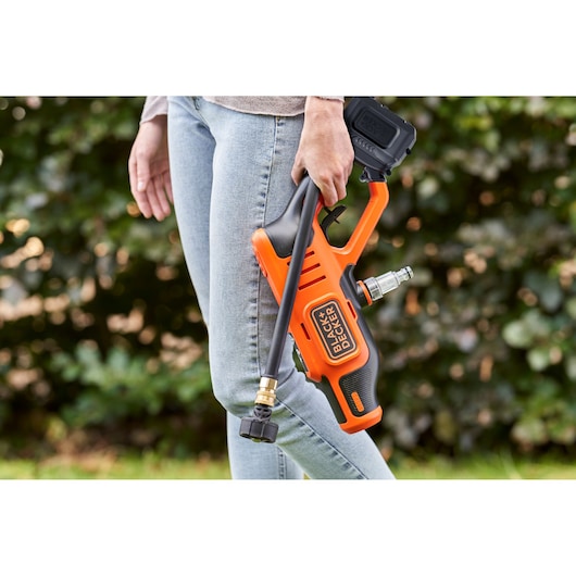 Photo of BLACKDECKER BZOQDW1 portable pressure washer held outdoors by person in jeans.