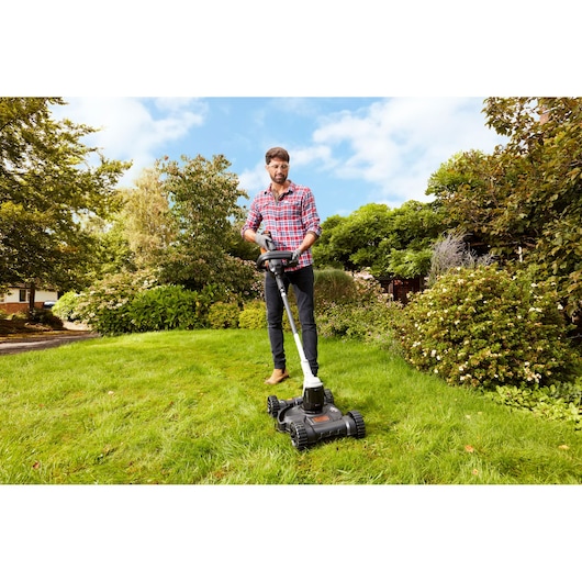 BLACKDECKER CM100 lawn mower being used on green grass outdoors.