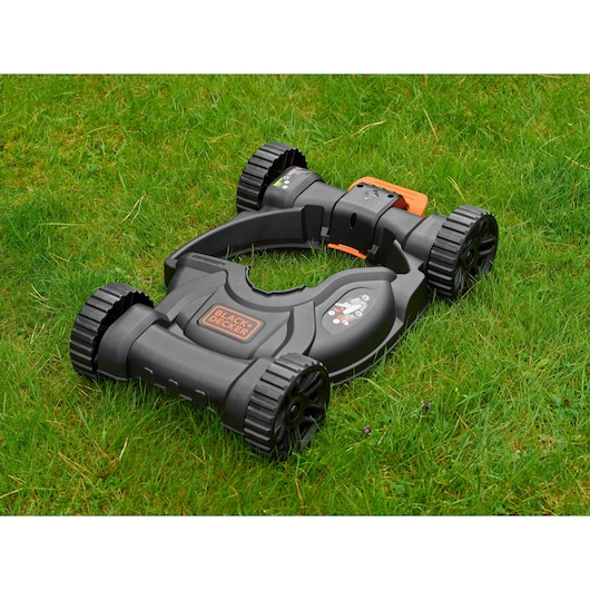 BLACKDECKER CM100 lawn mower accessory in black and orange on grass, side angle.